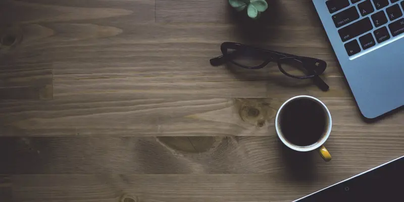 Image of a laptop computer and a cup of coffee on a wooden table