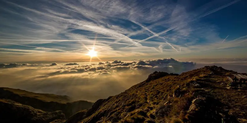 Image showing a range of mountains in the distance with blue sky, hazy clouds and a weak sun shining through